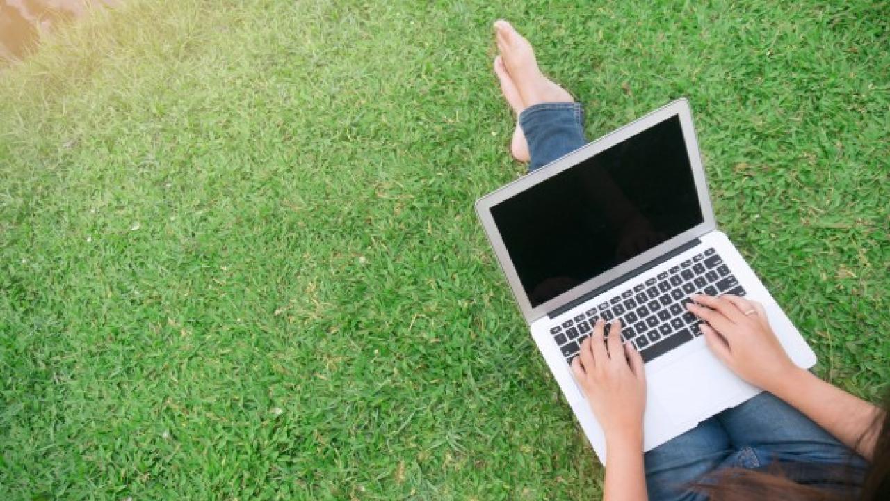 woman on laptop in grass